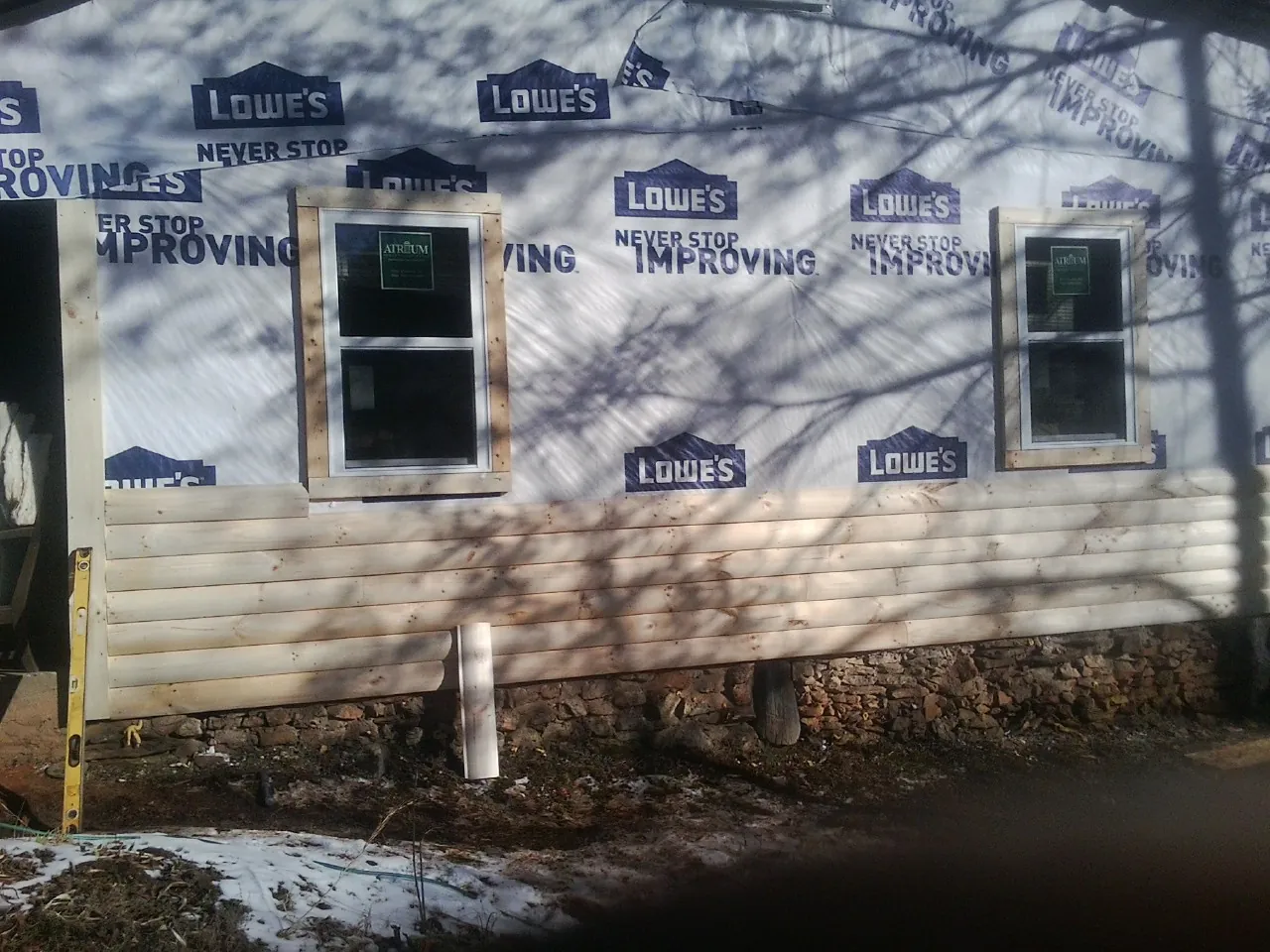 House wrap and new log siding going up on an exterior wall in North Clarendon