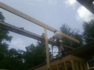 Carpenter setting a ridge beam over a new addition frame — Ice Dam Removal by Roofing Brothers in North Clarendon
