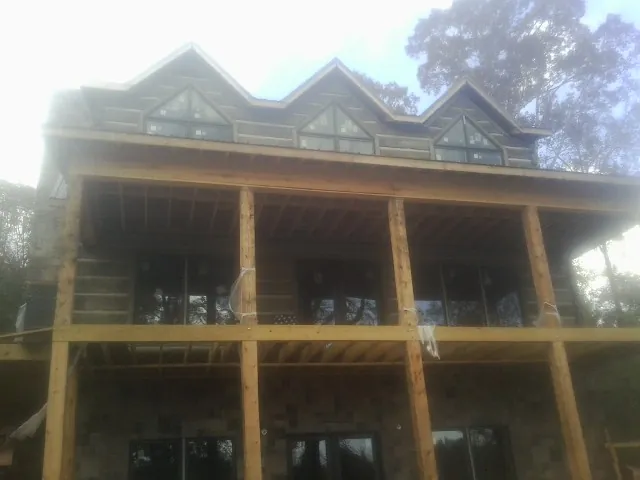 Dormers and porch framing on a large log home under construction — Roof Coating work by our crew in North Clarendon