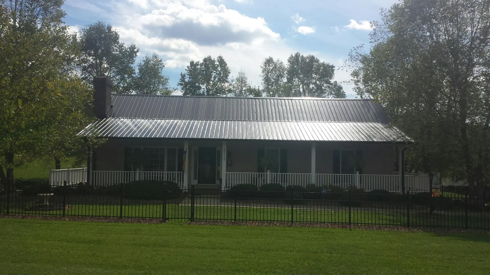 Gray metal roof on a brick ranch with a full width front porch — Gutter Guard Installation work by our crew in North Clarendon